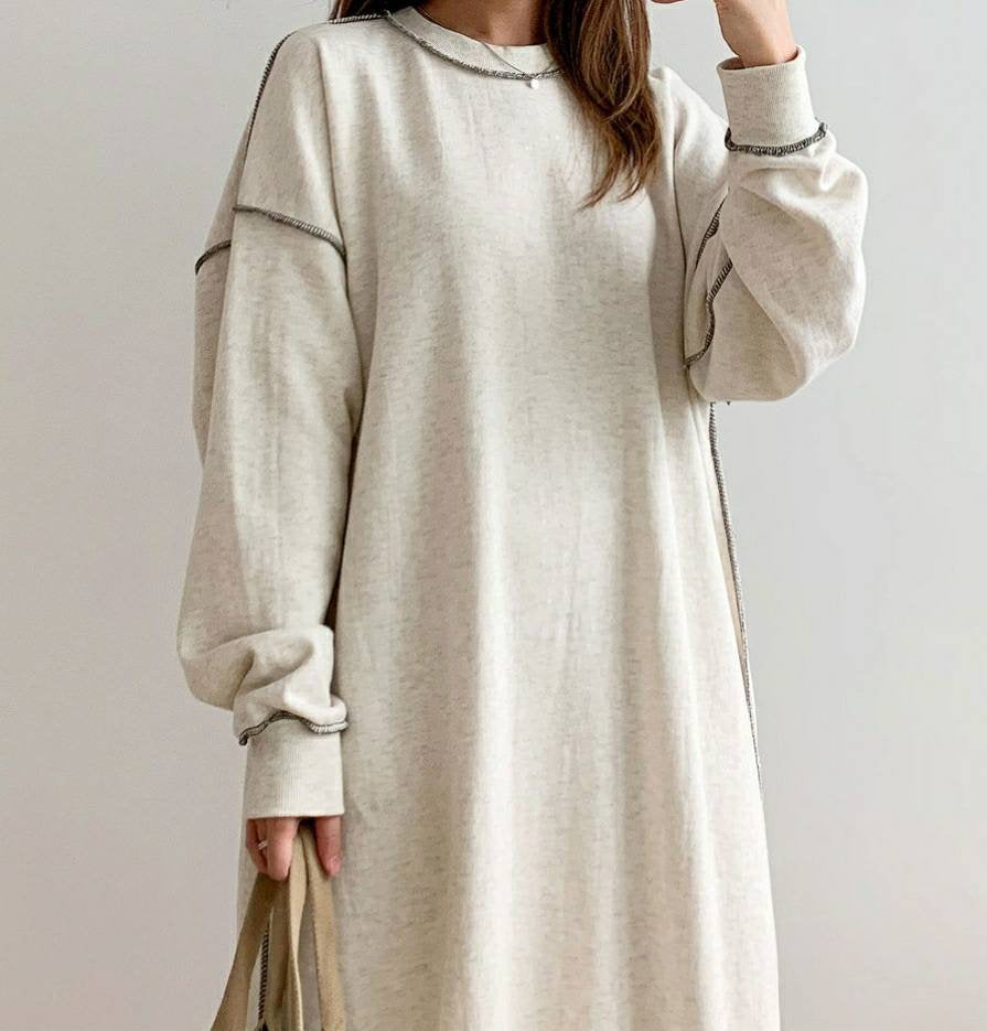 “Front view of an oversized oatmeal sweater dress with long sleeves and a relaxed minimalist fit.”